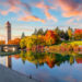 Vivid fall colors of red, orange, and yellow at the Spokane Washington Riverfront Park along the Spokane River with the Great Northern Clock Tower in view. Spokane is a city in eastern Washington state.